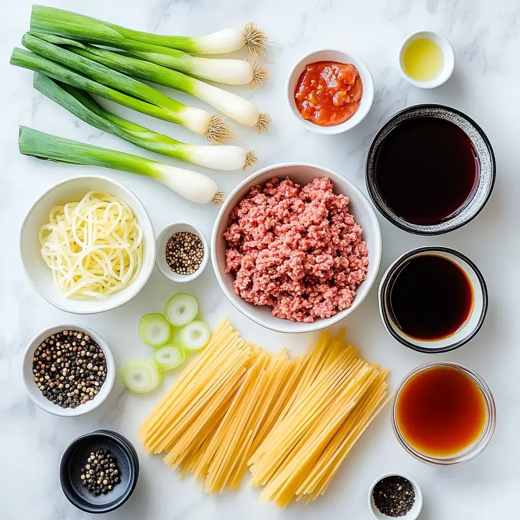 A spread of ingredients waiting to be cooked, like noodles, fresh green onions, sauces, spices, and ground meat, on a marble background.