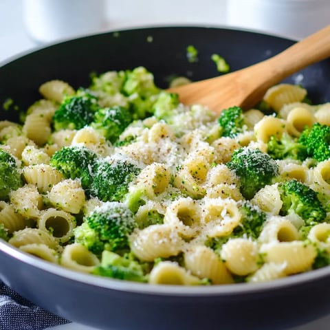 A bowl of pasta with broccoli and cheese.